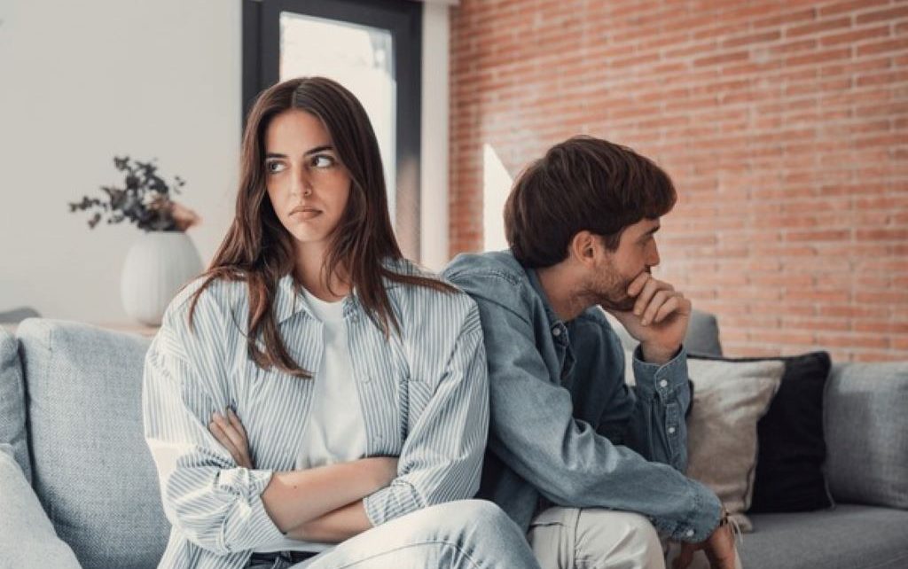 A couple sitting on a couch having a serious but calm discussion about their relationship