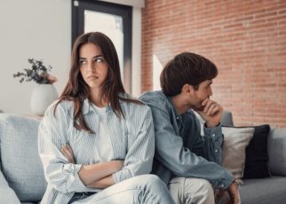 A couple sitting on a couch having a serious but calm discussion about their relationship