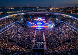 Aerial view of a packed Centre Stage audience at Web Summit Lisbon 2026, with bright lights illuminating the Altice Arena during the opening night keynote