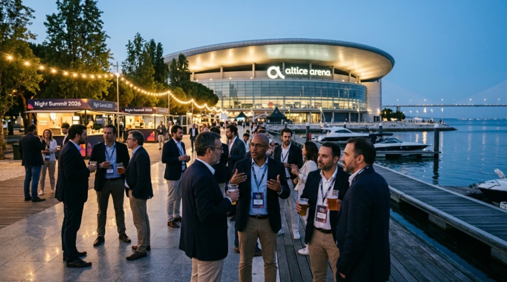 Attendees networking outdoors at Night Summit 2026, gathered near the waterfront in Lisbon's Parque das Nações district with the Altice Arena in the background